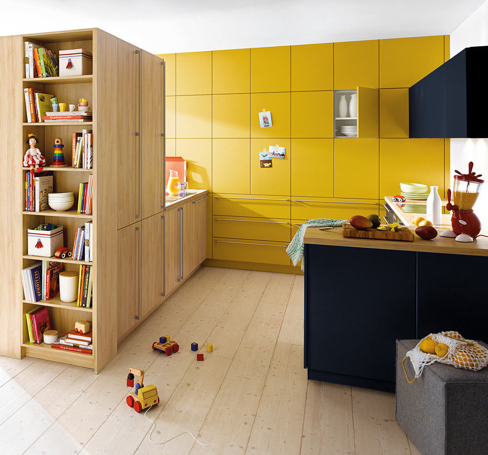 This is an example of a small modern galley separate kitchen in Surrey with flat-panel cabinets, yellow cabinets, laminate benchtops, light hardwood floors and a peninsula.
