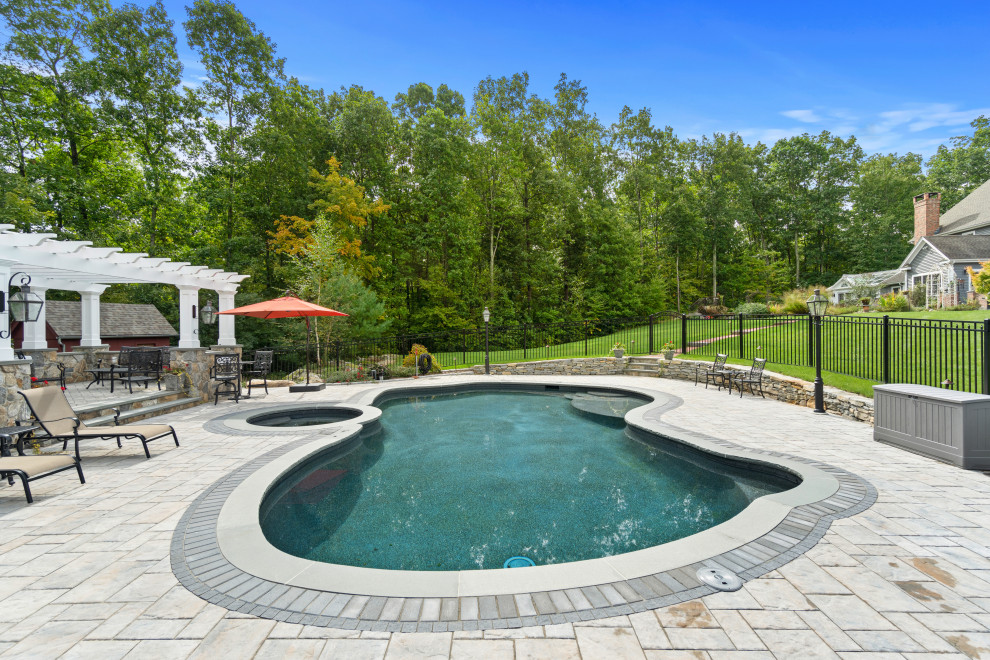 Inspiration for a large traditional backyard custom-shaped pool in Bridgeport with concrete pavers.