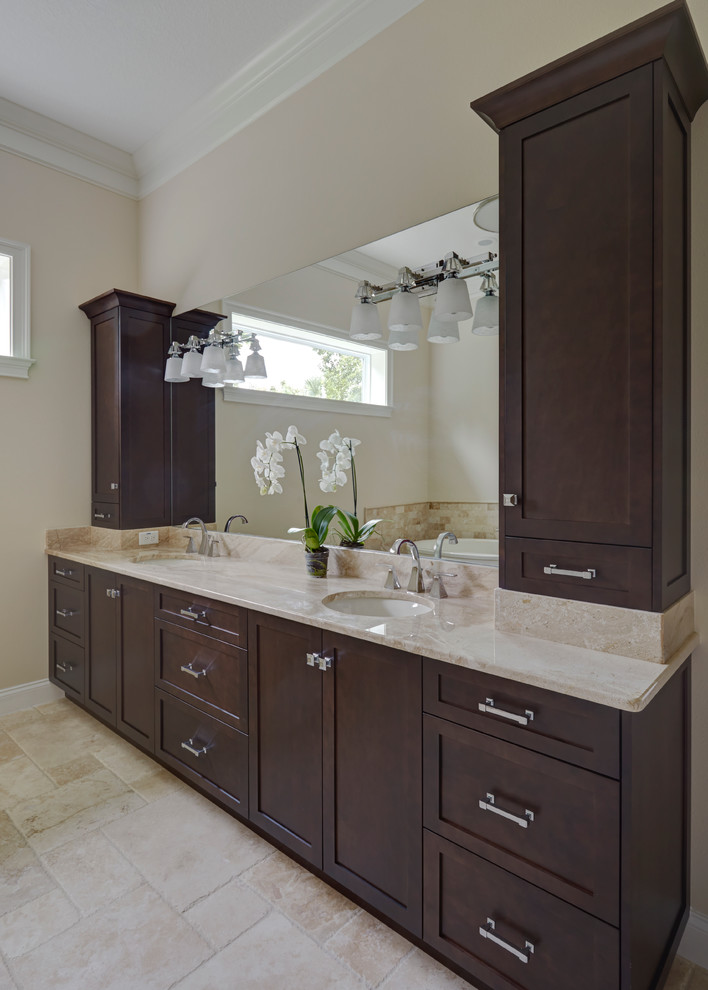 Inspiration for a mid-sized modern master bathroom in Orlando with shaker cabinets, dark wood cabinets, a freestanding tub, beige tile, stone tile, beige walls, ceramic floors, an undermount sink, granite benchtops and beige floor.
