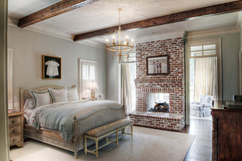 Design ideas for a mid-sized traditional master bedroom in Other with grey walls, medium hardwood floors, a brick fireplace surround and a two-sided fireplace.