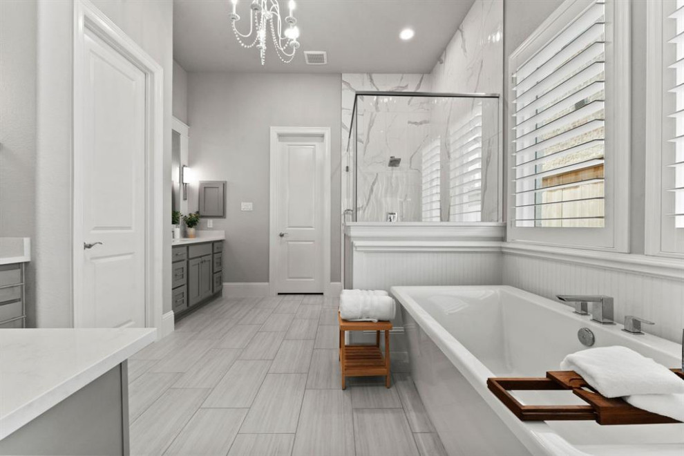На фото: большая главная ванная комната в стиле кантри с фасадами в стиле шейкер, серыми фасадами, отдельно стоящей ванной, двойным душем, белой плиткой, керамической плиткой, серыми стенами, полом из керамической плитки, врезной раковиной, серым полом, душем с распашными дверями, белой столешницей, сиденьем для душа, тумбой под две раковины, встроенной тумбой, унитазом-моноблоком и столешницей из искусственного кварца