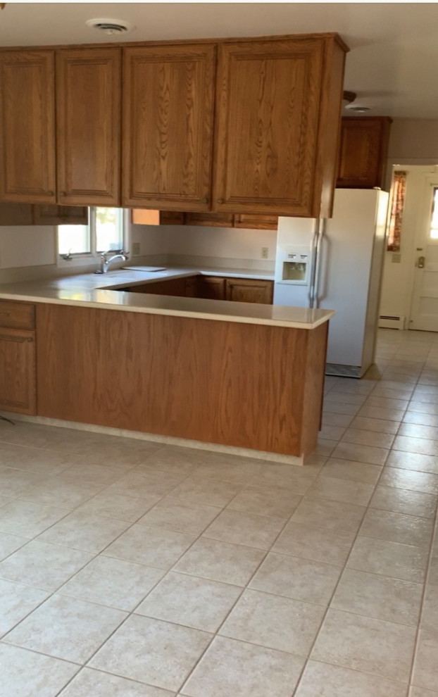Eat-in kitchen - small transitional u-shaped ceramic tile and brown floor eat-in kitchen idea with an integrated sink, raised-panel cabinets, brown cabinets, solid surface countertops, white appliances, a peninsula and brown countertops