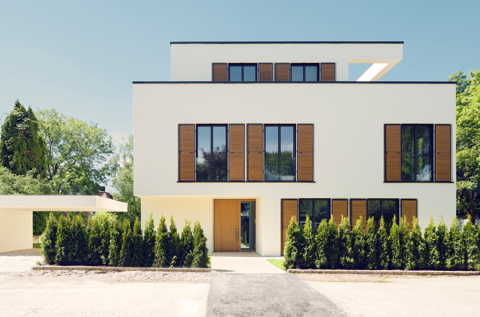 This is an example of a large contemporary three-storey white exterior in Munich with a flat roof.