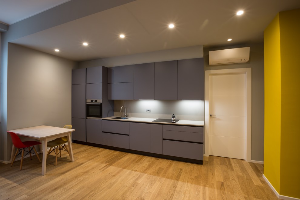 This is an example of a small contemporary single-wall eat-in kitchen in Milan with flat-panel cabinets, turquoise cabinets and solid surface benchtops.