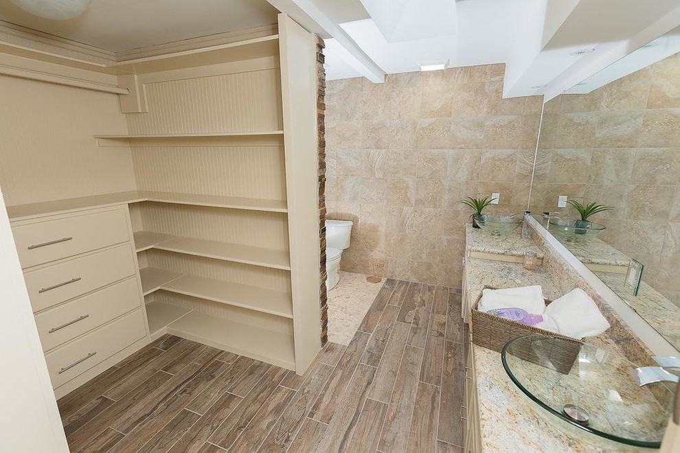 Mid-sized contemporary 3/4 bathroom in Houston with raised-panel cabinets, beige cabinets, an alcove shower, a one-piece toilet, beige tile, stone tile, beige walls, ceramic floors, a vessel sink, granite benchtops, beige floor and a hinged shower door.