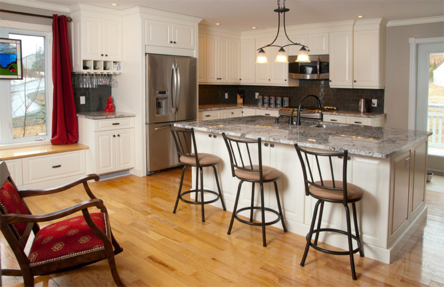 Eat-in kitchen - mid-sized transitional l-shaped light wood floor eat-in kitchen idea with an undermount sink, raised-panel cabinets, white cabinets, granite countertops, gray backsplash, glass tile backsplash, stainless steel appliances and an island