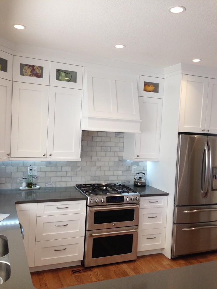 Design ideas for a large traditional u-shaped eat-in kitchen in Denver with an undermount sink, shaker cabinets, white cabinets, quartz benchtops, white splashback, subway tile splashback, stainless steel appliances, medium hardwood floors and a peninsula.