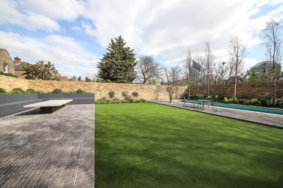 Photo of a mid-sized modern backyard full sun formal garden for summer in London with with flowerbed and natural stone pavers.
