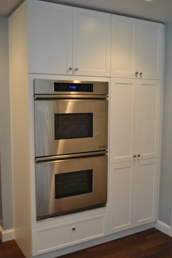 Inspiration for a mid-sized transitional galley medium tone wood floor eat-in kitchen remodel with an undermount sink, shaker cabinets, white cabinets, quartz countertops, multicolored backsplash, glass sheet backsplash, stainless steel appliances and no island