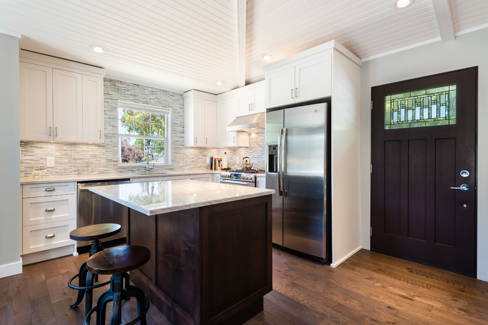 Inspiration for a small transitional l-shaped medium tone wood floor and brown floor open concept kitchen remodel in Vancouver with an undermount sink, recessed-panel cabinets, white cabinets, quartzite countertops, gray backsplash, matchstick tile backsplash, stainless steel appliances and an island
