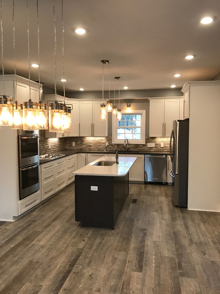 Mid-sized transitional u-shaped medium tone wood floor and brown floor eat-in kitchen photo in Charleston with an undermount sink, shaker cabinets, white cabinets, quartzite countertops, brown backsplash, stone tile backsplash, stainless steel appliances and an island