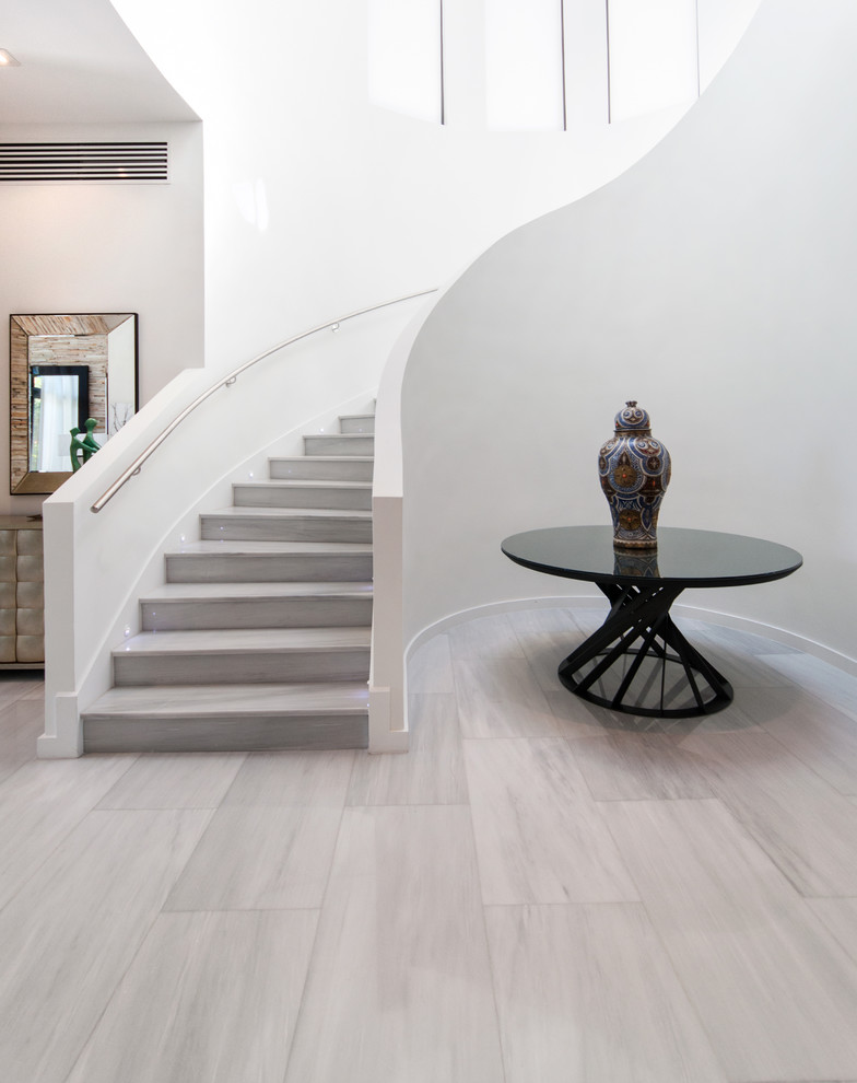 Large contemporary marble curved staircase in Miami with marble risers.