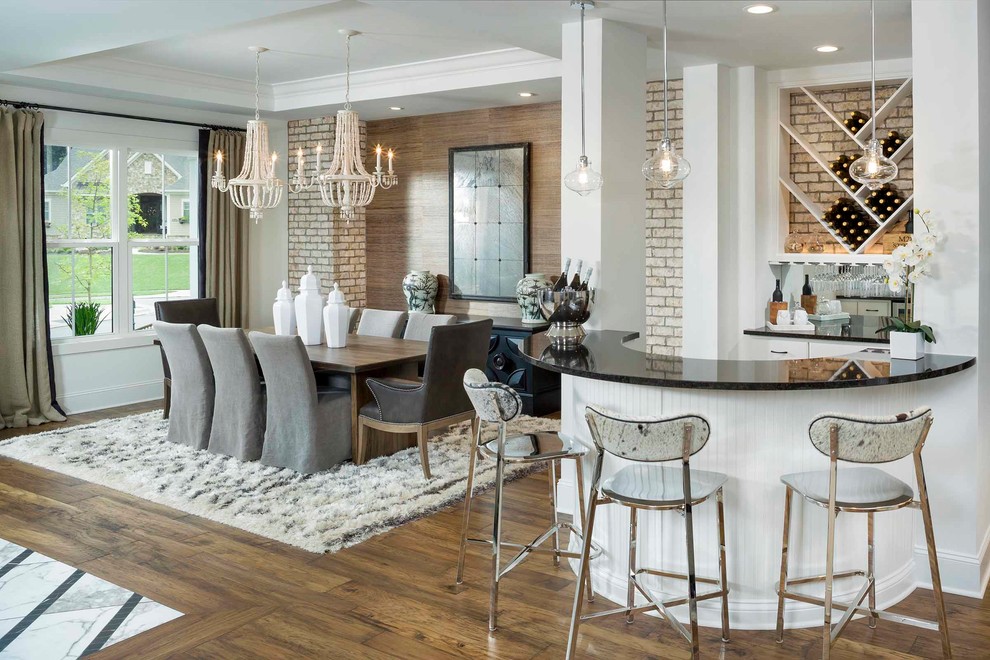 Design ideas for a transitional seated home bar in Charlotte with white cabinets, mirror splashback, dark hardwood floors, brown floor and black benchtop.