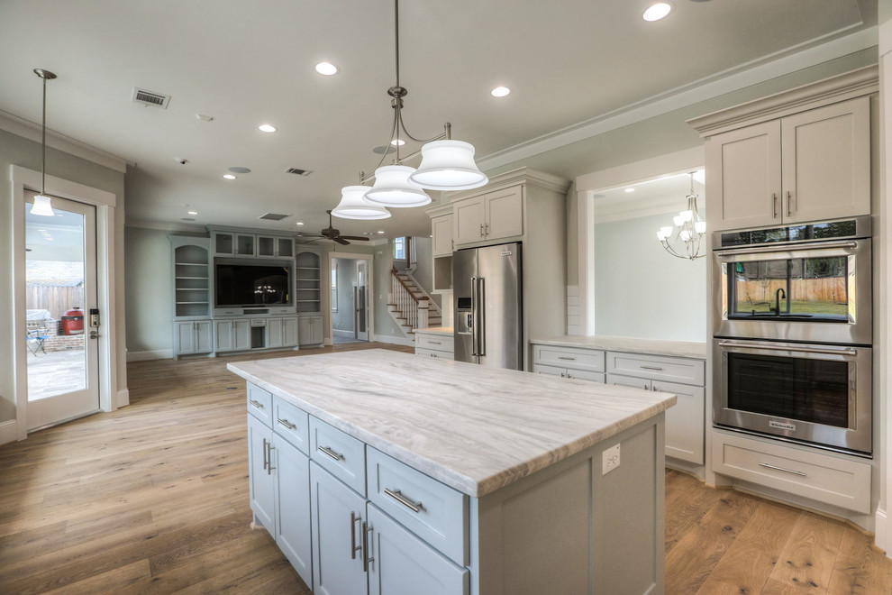 Enclosed kitchen - mid-sized transitional u-shaped light wood floor and beige floor enclosed kitchen idea in Houston with shaker cabinets, gray cabinets, white backsplash, stainless steel appliances, an island, a double-bowl sink, quartz countertops and subway tile backsplash