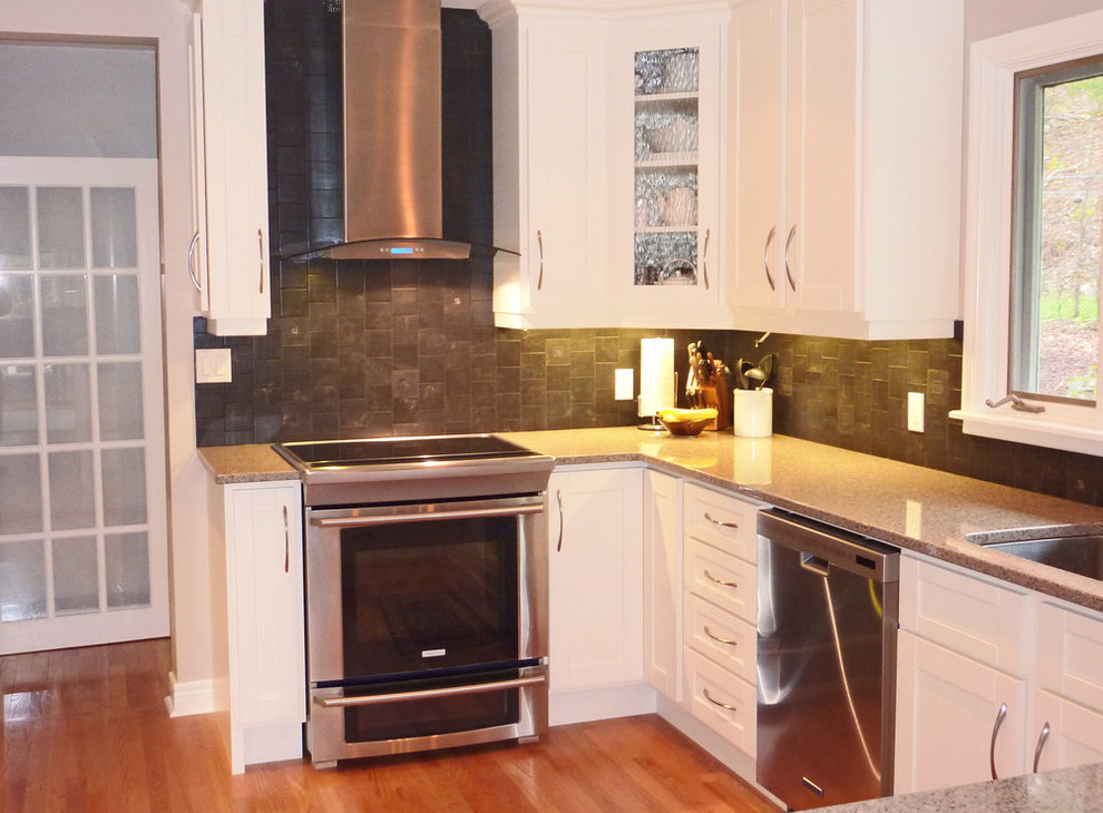 Example of a small transitional u-shaped medium tone wood floor and brown floor open concept kitchen design with shaker cabinets, white cabinets, granite countertops, gray backsplash, stainless steel appliances, a peninsula and gray countertops