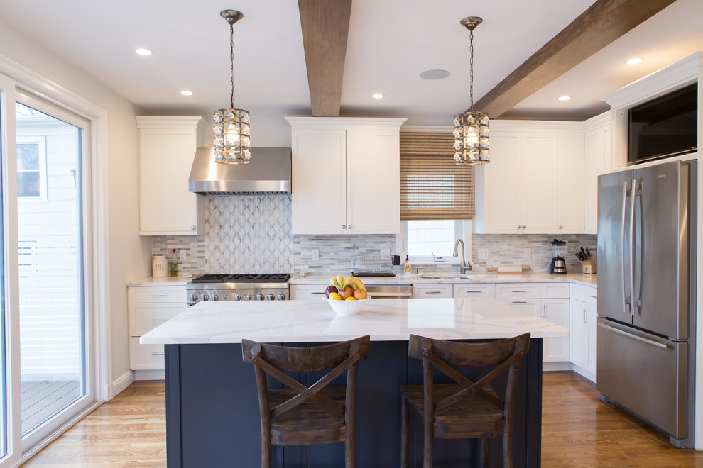 Inspiration for a mid-sized transitional l-shaped open plan kitchen in Boston with a single-bowl sink, shaker cabinets, white cabinets, marble benchtops, white splashback, marble splashback, stainless steel appliances, medium hardwood floors and with island.