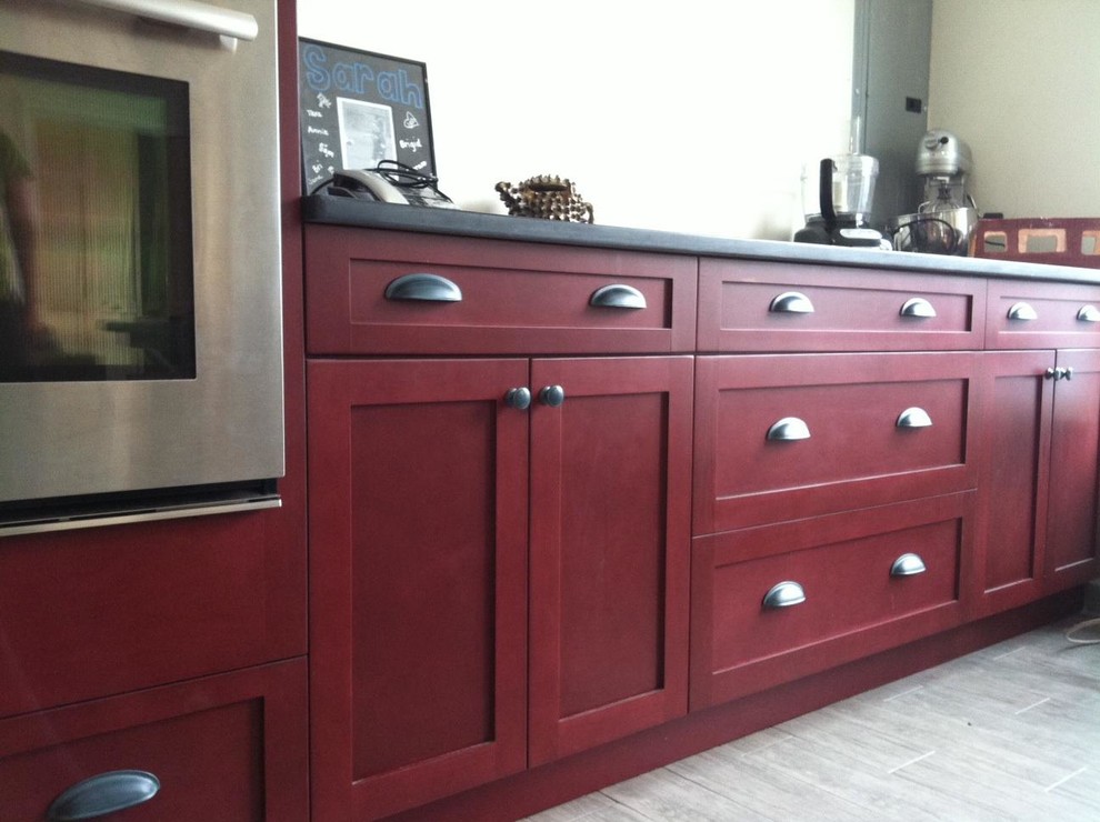 Example of a mid-sized transitional ceramic tile eat-in kitchen design with flat-panel cabinets, red cabinets, solid surface countertops, stainless steel appliances, white walls and an island