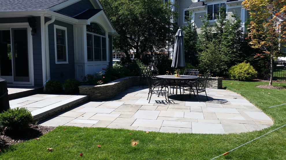Large traditional backyard patio in New York with natural stone pavers.