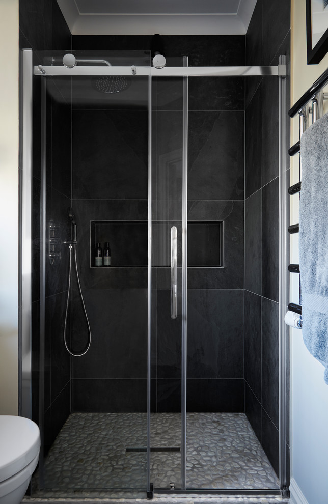 Photo of a small contemporary master bathroom in London with flat-panel cabinets, grey cabinets, a curbless shower, a wall-mount toilet, gray tile, travertine, beige walls, pebble tile floors, a pedestal sink, solid surface benchtops, beige floor and a sliding shower screen.