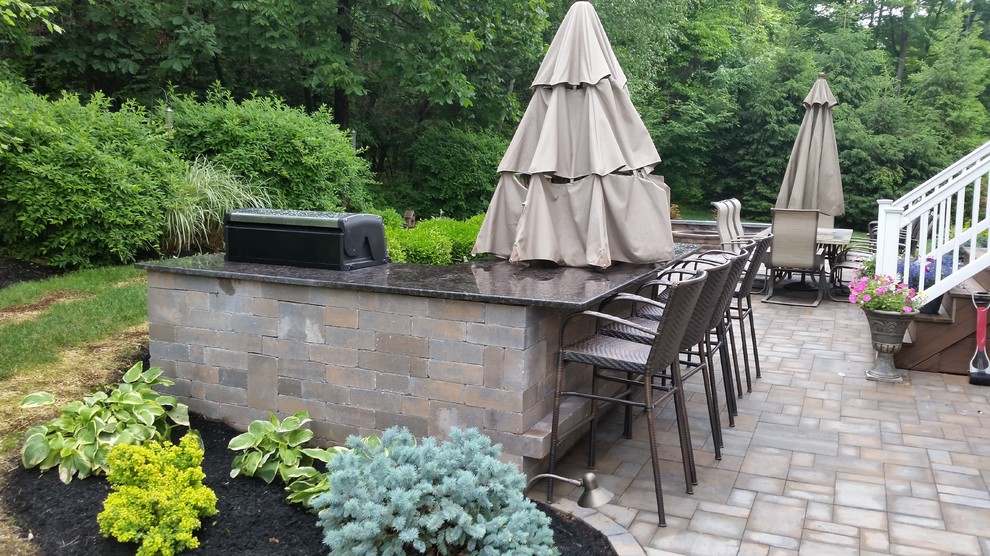Design ideas for a mid-sized traditional backyard patio in New York with an outdoor kitchen and natural stone pavers.