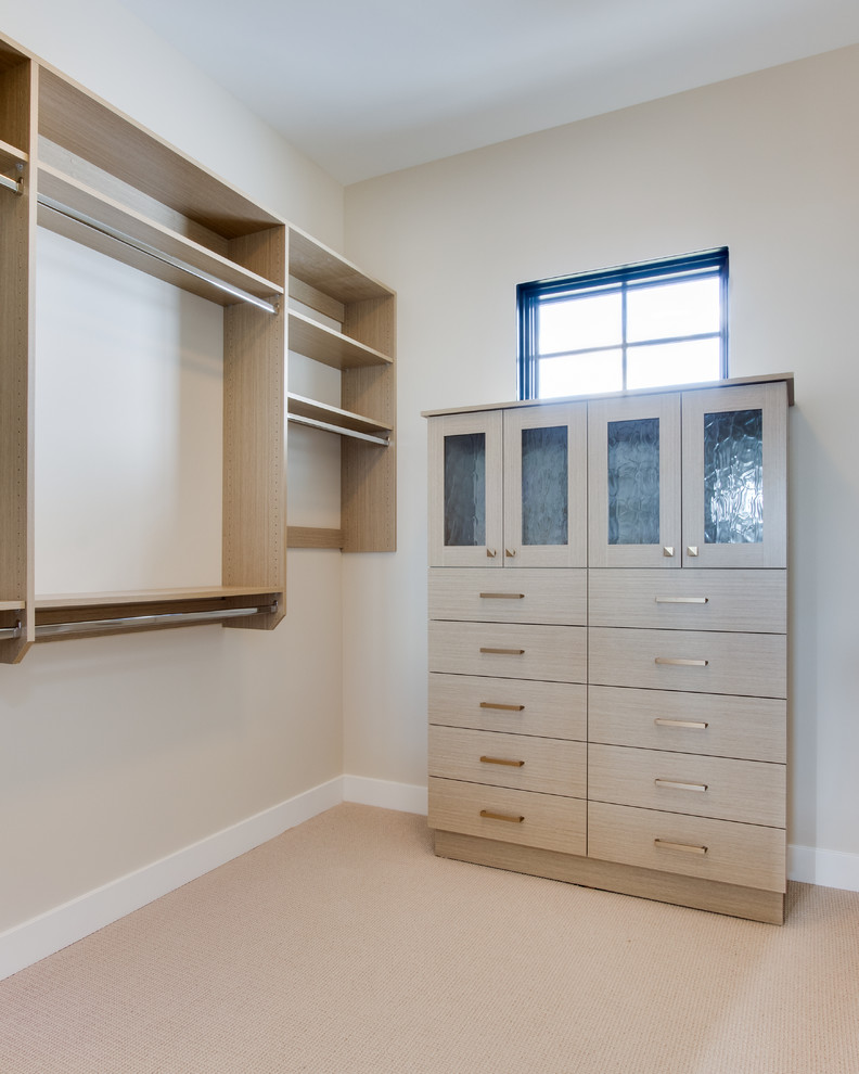 This is an example of a country gender-neutral walk-in wardrobe in Salt Lake City with flat-panel cabinets, light wood cabinets, carpet and beige floor.