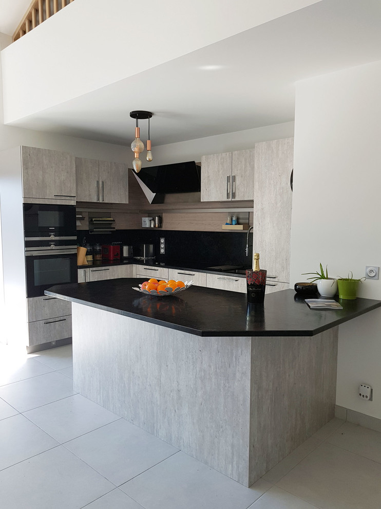 Mid-sized industrial l-shaped eat-in kitchen in Other with an undermount sink, granite benchtops, black splashback, black appliances, ceramic floors, a peninsula, grey floor and black benchtop.