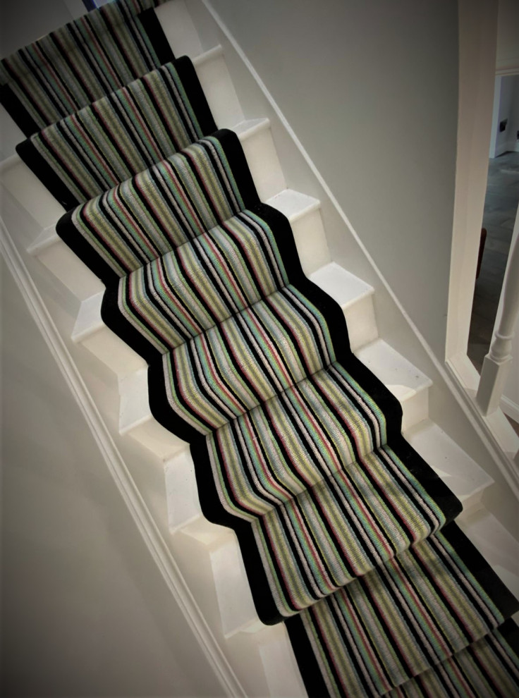 Photo of a large contemporary carpeted straight staircase in Hertfordshire with carpet risers and wood railing.