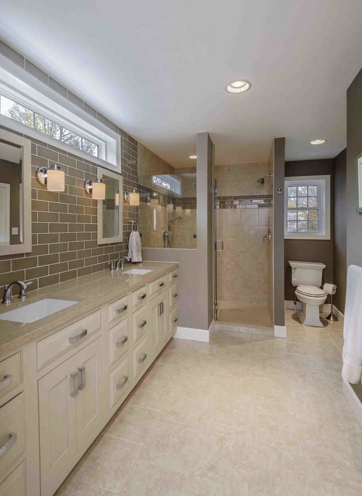 Example of a mid-sized classic master beige tile and subway tile ceramic tile and beige floor alcove shower design in Other with an undermount sink, raised-panel cabinets, beige cabinets, a two-piece toilet, gray walls and quartz countertops