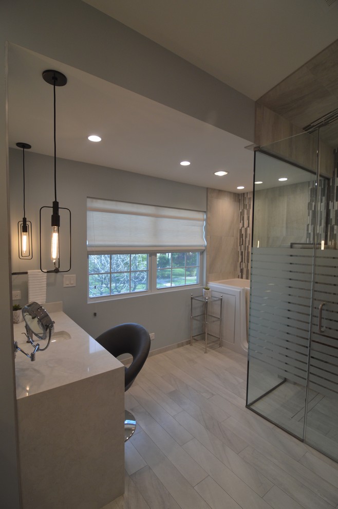 Photo of a large modern master bathroom in Chicago with flat-panel cabinets, grey cabinets, an alcove tub, a curbless shower, a one-piece toilet, gray tile, porcelain tile, blue walls, porcelain floors, an undermount sink, engineered quartz benchtops, grey floor and a hinged shower door.
