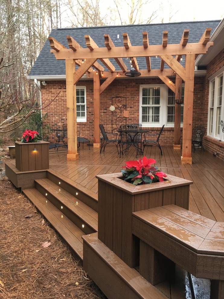 Large elegant backyard deck photo with a pergola