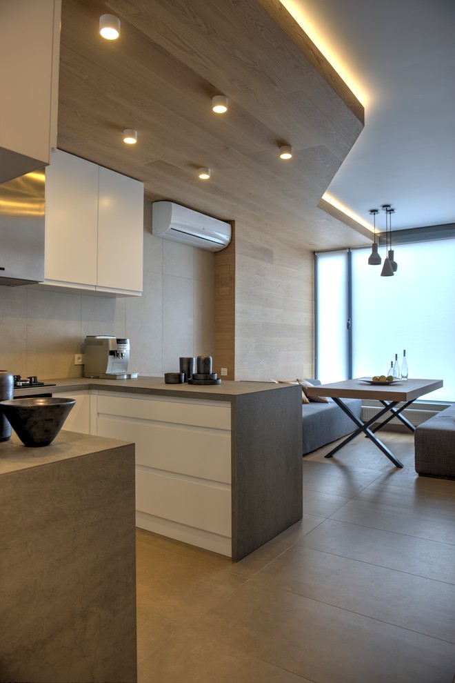Mid-sized contemporary u-shaped eat-in kitchen in Other with a single-bowl sink, recessed-panel cabinets, white cabinets, tile benchtops, beige splashback, porcelain splashback, stainless steel appliances, ceramic floors and beige floor.