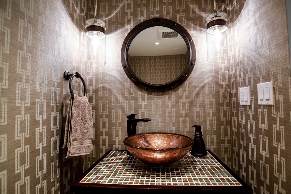 This is an example of a small contemporary powder room in Miami with furniture-like cabinets, medium wood cabinets, brown tile, brown walls, a vessel sink and tile benchtops.