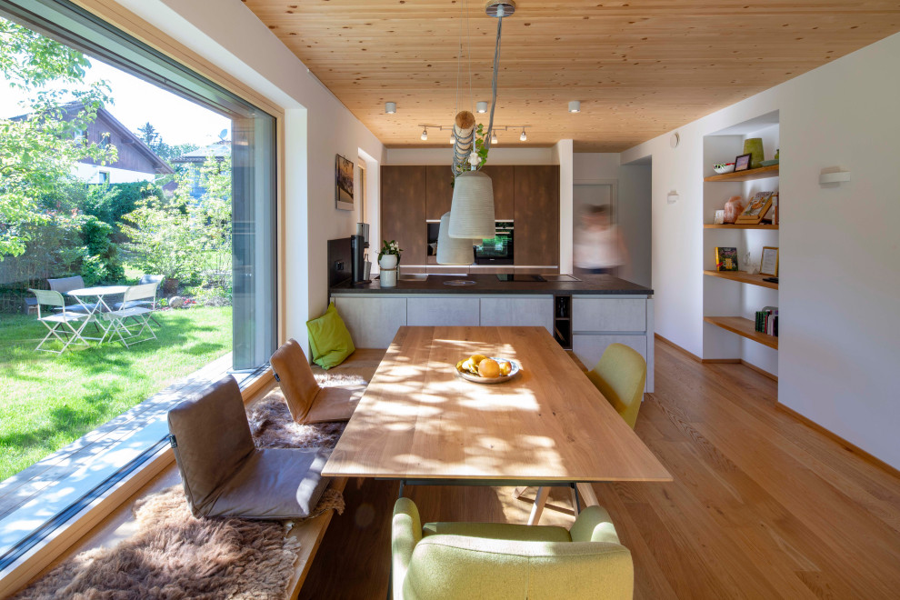 Réalisation d'une salle à manger ouverte sur le salon design avec un sol en bois brun, un poêle à bois et un plafond en bois.