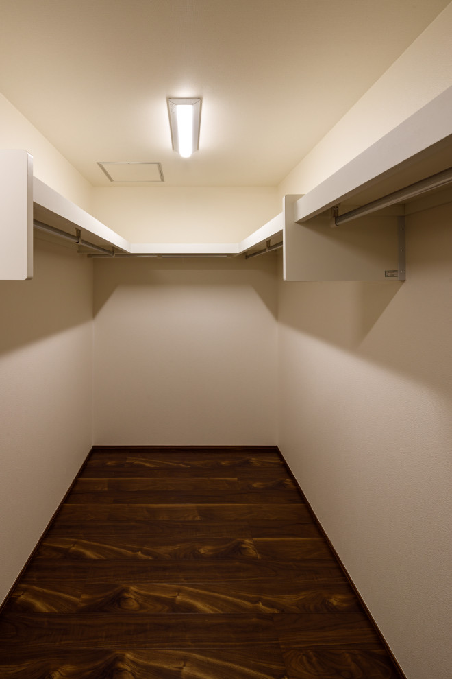 Large modern gender-neutral walk-in wardrobe in Other with plywood floors, brown floor and wallpaper.