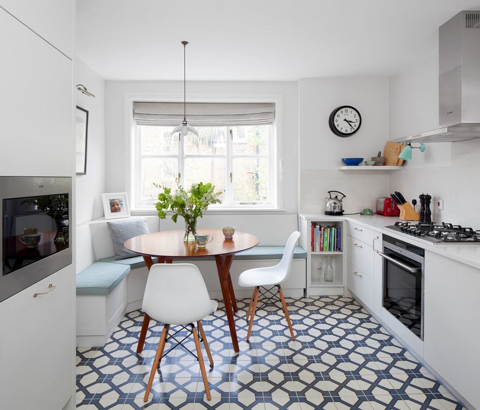 This is an example of a small contemporary galley eat-in kitchen in London with flat-panel cabinets, white cabinets, ceramic floors and no island.