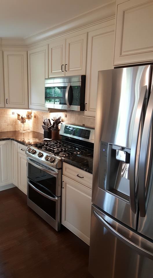 Kitchen - mid-sized transitional l-shaped dark wood floor kitchen idea in Baltimore with white cabinets, beige backsplash, stainless steel appliances and an island