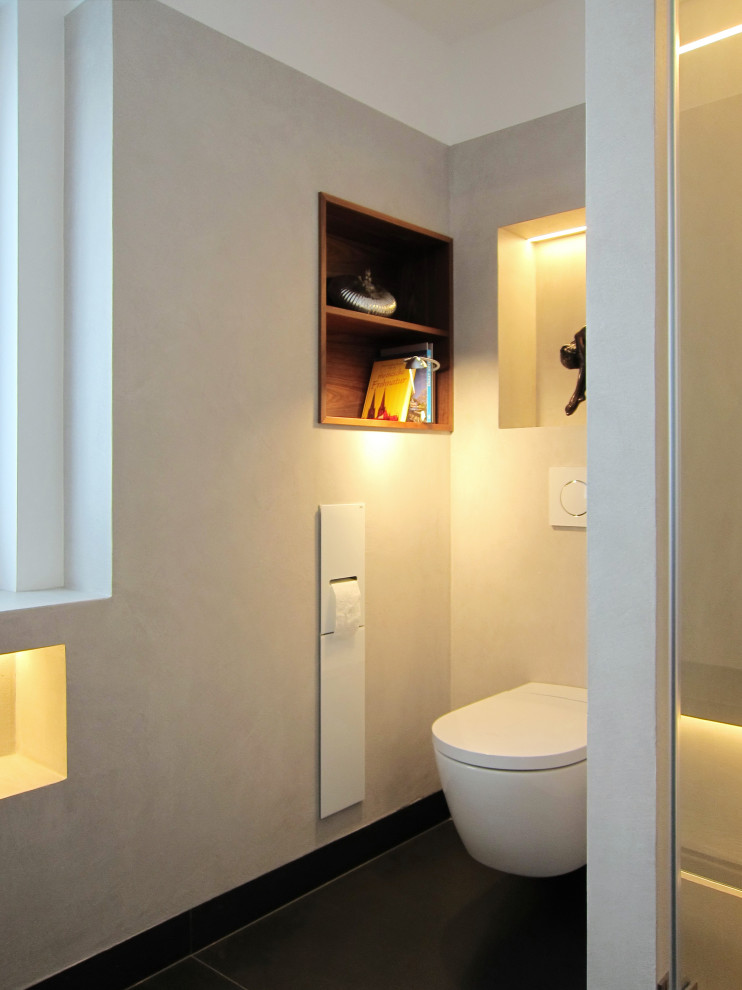 Idéer för mellanstora funkis grått badrum med dusch, med släta luckor, skåp i mörkt trä, en dusch i en alkov, en vägghängd toalettstol, grå kakel, vita väggar, klinkergolv i keramik, ett fristående handfat och svart golv