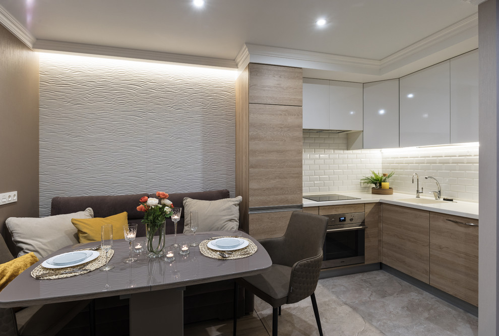 Photo of a small contemporary l-shaped eat-in kitchen in Saint Petersburg with an undermount sink, flat-panel cabinets, white cabinets, solid surface benchtops, multi-coloured splashback, ceramic splashback, stainless steel appliances, porcelain floors, no island and beige floor.