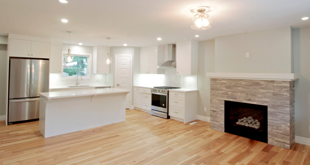 Eat-in kitchen - mid-sized transitional l-shaped light wood floor eat-in kitchen idea with a double-bowl sink, shaker cabinets, white cabinets, solid surface countertops, white backsplash, ceramic backsplash, stainless steel appliances, an island and white countertops