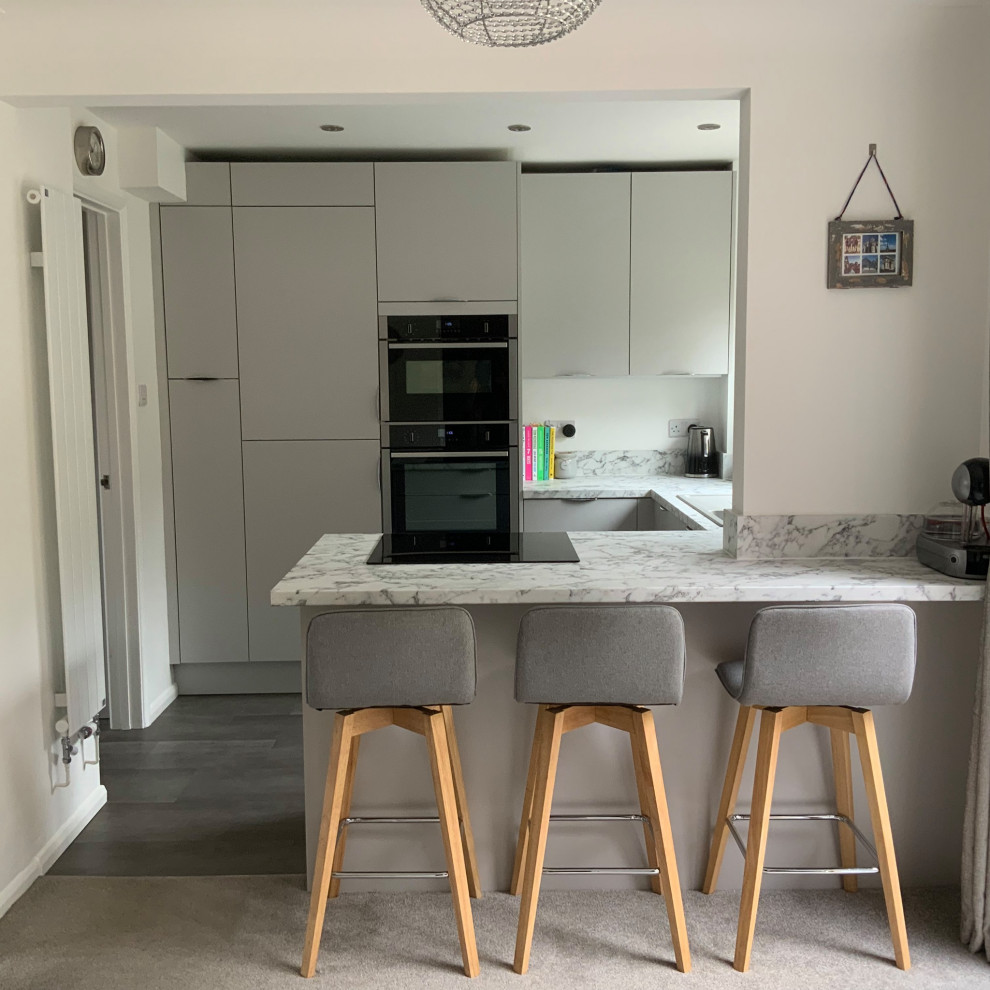 Inspiration for a small contemporary grey and white u-shaped kitchen/diner in Buckinghamshire with flat-panel cabinets, grey cabinets, laminate countertops, integrated appliances, a breakfast bar and grey worktops.