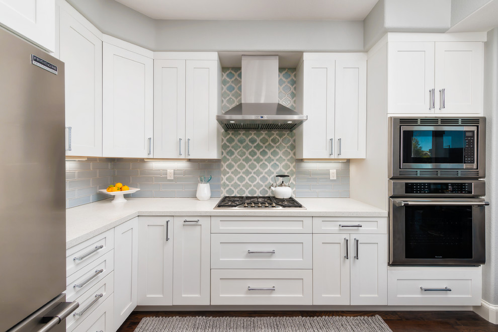 This is an example of a small transitional l-shaped open plan kitchen in San Francisco with an undermount sink, shaker cabinets, white cabinets, quartz benchtops, blue splashback, ceramic splashback, stainless steel appliances, dark hardwood floors, with island and brown floor.