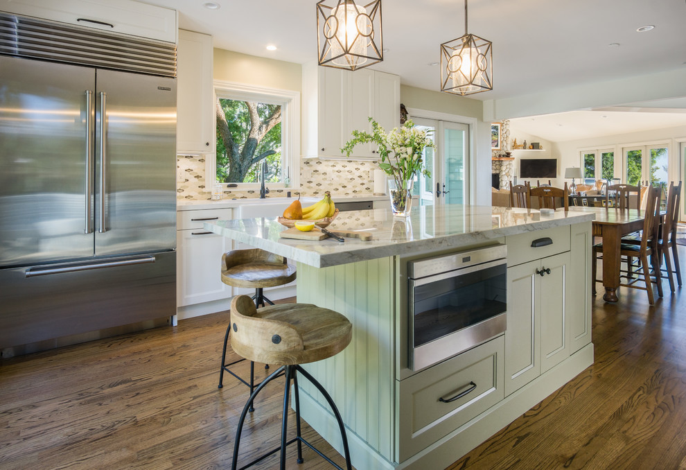 This is an example of a mid-sized transitional eat-in kitchen in Los Angeles with a farmhouse sink, recessed-panel cabinets, white cabinets, quartzite benchtops, green splashback, mosaic tile splashback, stainless steel appliances, medium hardwood floors and with island.