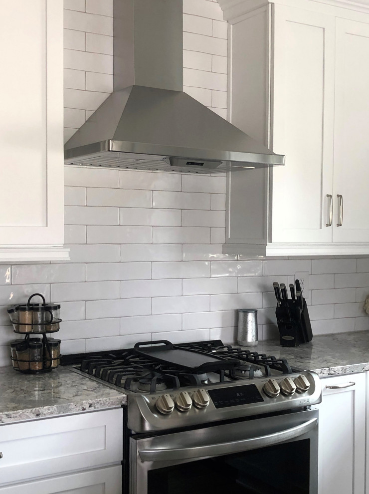 Inspiration for a mid-sized transitional l-shaped vinyl floor and multicolored floor eat-in kitchen remodel with an undermount sink, flat-panel cabinets, green cabinets, quartz countertops, white backsplash, ceramic backsplash, stainless steel appliances, an island and gray countertops