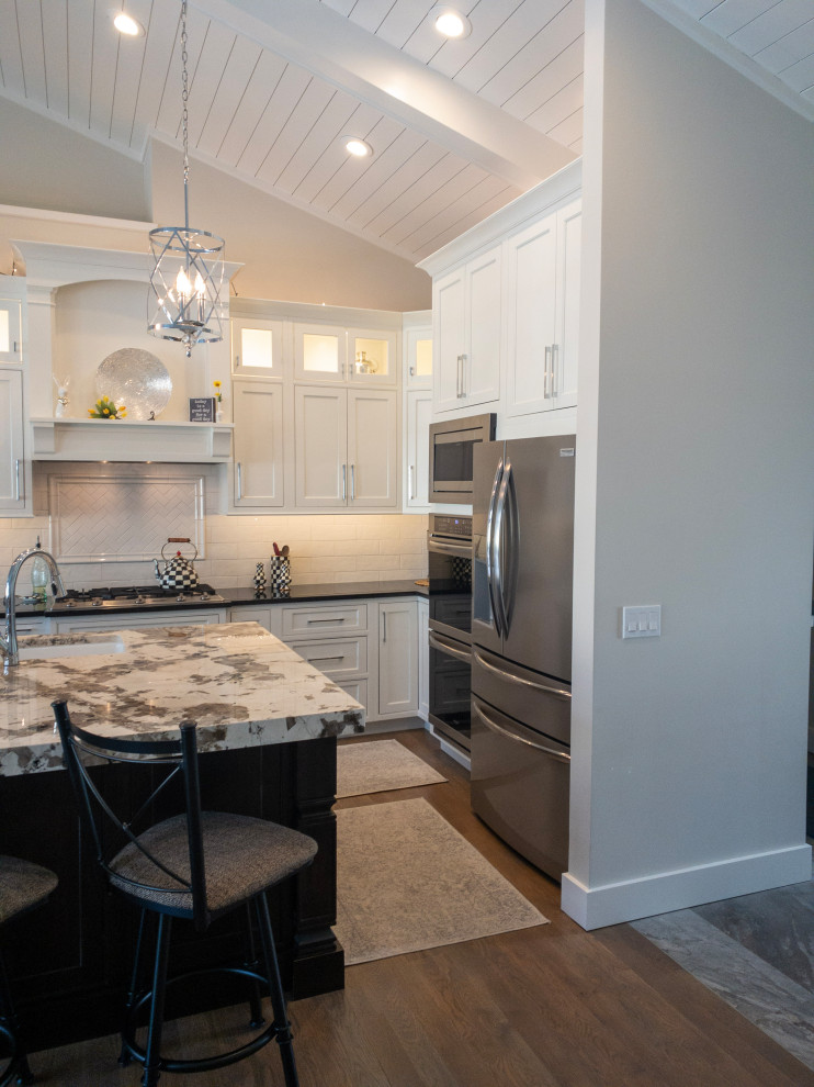 Example of a large transitional l-shaped medium tone wood floor, gray floor and shiplap ceiling eat-in kitchen design with an undermount sink, flat-panel cabinets, white cabinets, granite countertops, yellow backsplash, subway tile backsplash, stainless steel appliances, an island and white countertops