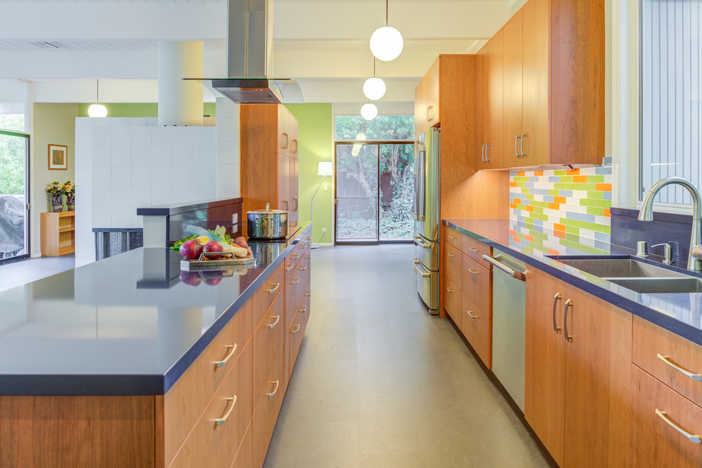 Mid-sized midcentury galley open plan kitchen in San Francisco with an undermount sink, flat-panel cabinets, dark wood cabinets, quartz benchtops, multi-coloured splashback, stainless steel appliances, no island, grey floor, blue benchtop and glass tile splashback.