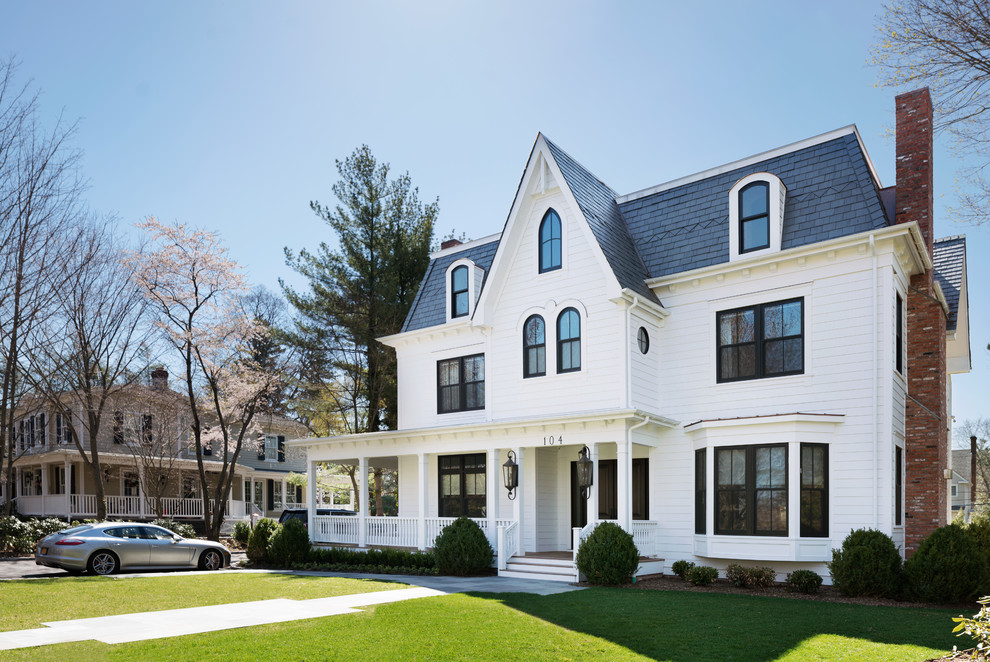 Photo of a large traditional three-storey white house exterior in New York with vinyl siding and a shingle roof.