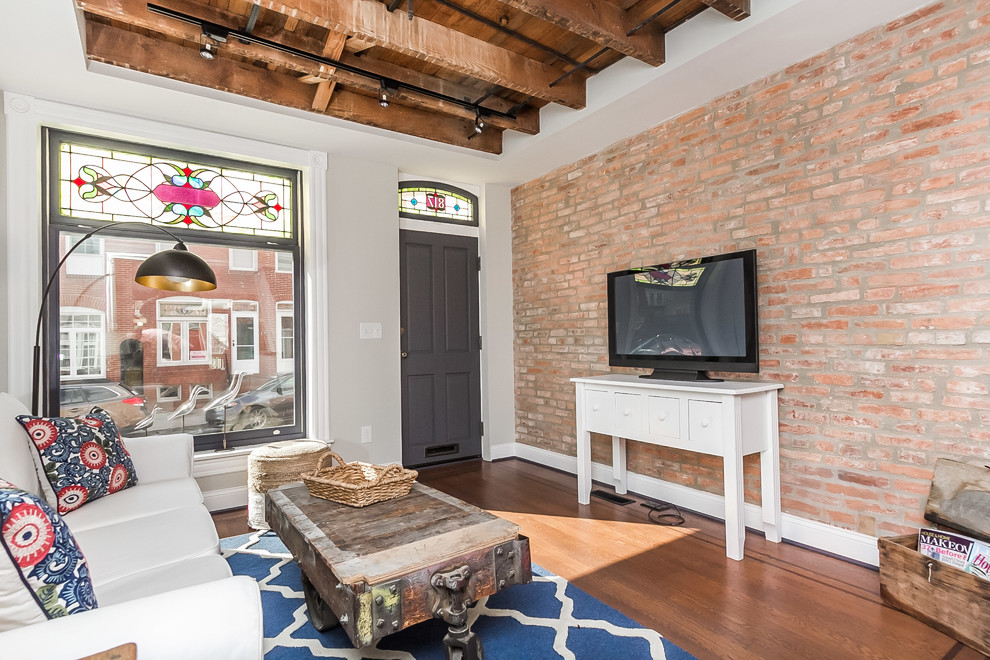 This is an example of a mid-sized industrial enclosed living room in Baltimore with white walls, no fireplace, medium hardwood floors, a freestanding tv and brown floor.