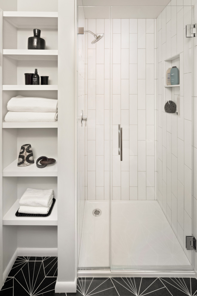 На фото: маленькая ванная комната в стиле модернизм с плоскими фасадами, фасадами цвета дерева среднего тона, душем в нише, раздельным унитазом, белой плиткой, керамической плиткой, серыми стенами, полом из керамической плитки, душевой кабиной, монолитной раковиной, столешницей из искусственного камня, черным полом, душем с распашными дверями, белой столешницей, нишей и тумбой под одну раковину для на участке и в саду с
