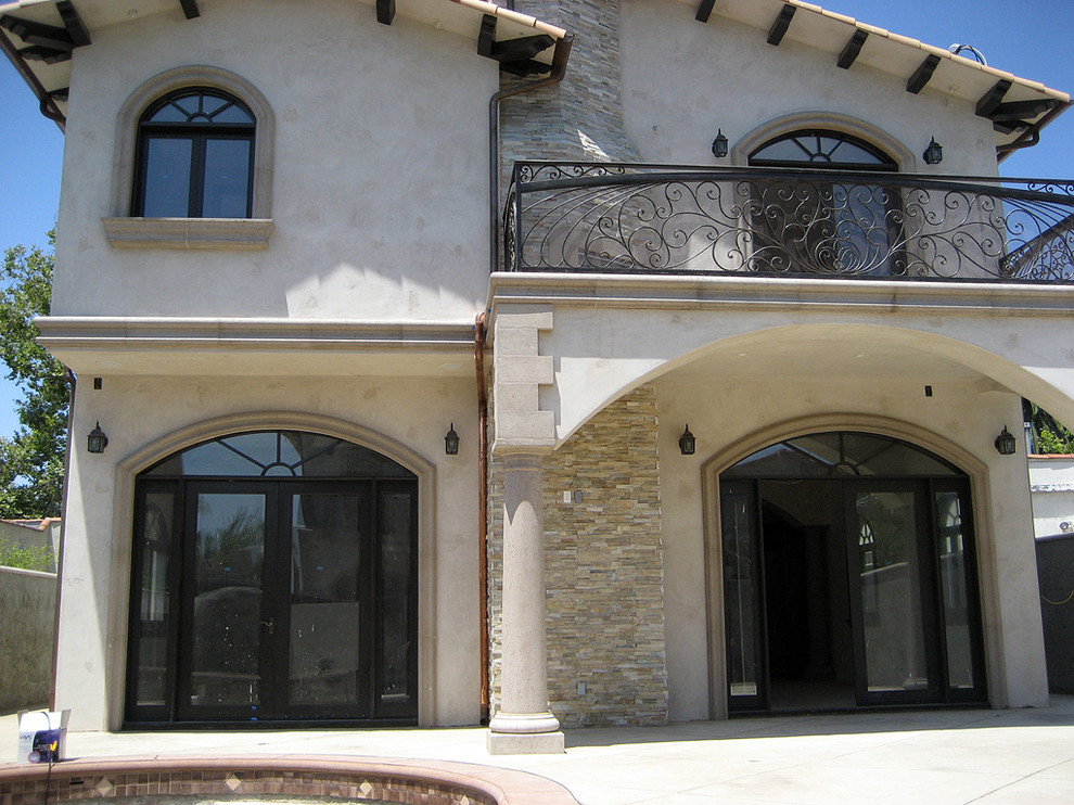 Photo of a mid-sized transitional two-storey stucco beige house exterior in Los Angeles with a gable roof and a tile roof.