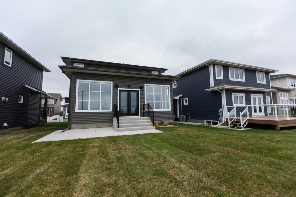 This is an example of a mid-sized contemporary two-storey grey exterior in Other with vinyl siding and a hip roof.